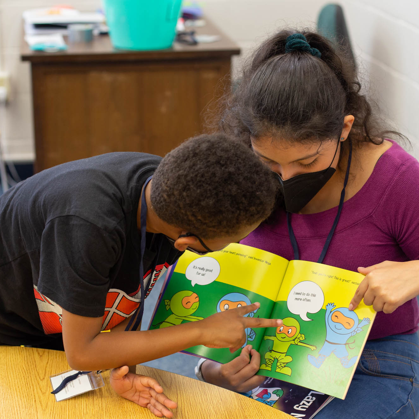 A student and teacher reading a book.